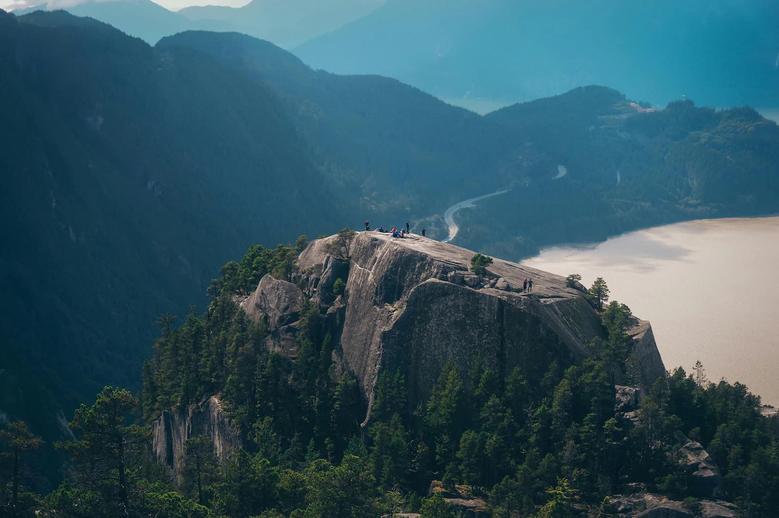 Calm forest lake edged with evergreens, quiet water and soft light for a small-group day outside